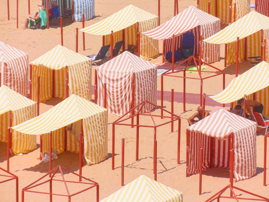 Stripe-patterned tents on a beach create a vibrant scene in Peniche, Portugal.
