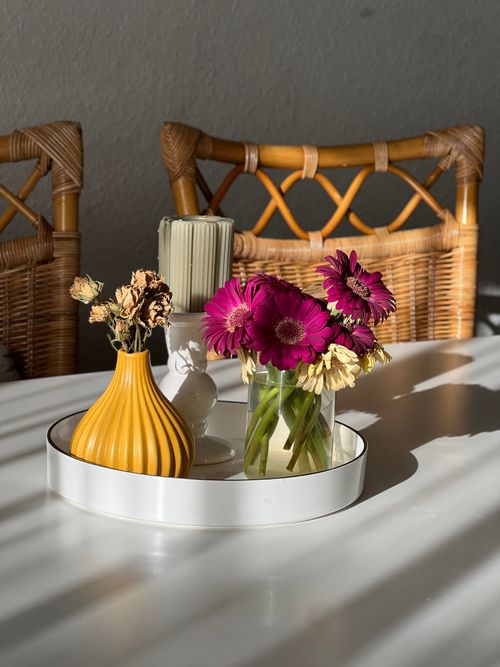 Free Sunlit table with vibrant flowers and wicker chairs for a cozy atmosphere. Stock Photo