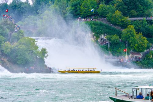 Free Vibrant shot of Rhine Falls with tourist boats and lush greenery during summer. Stock Photo