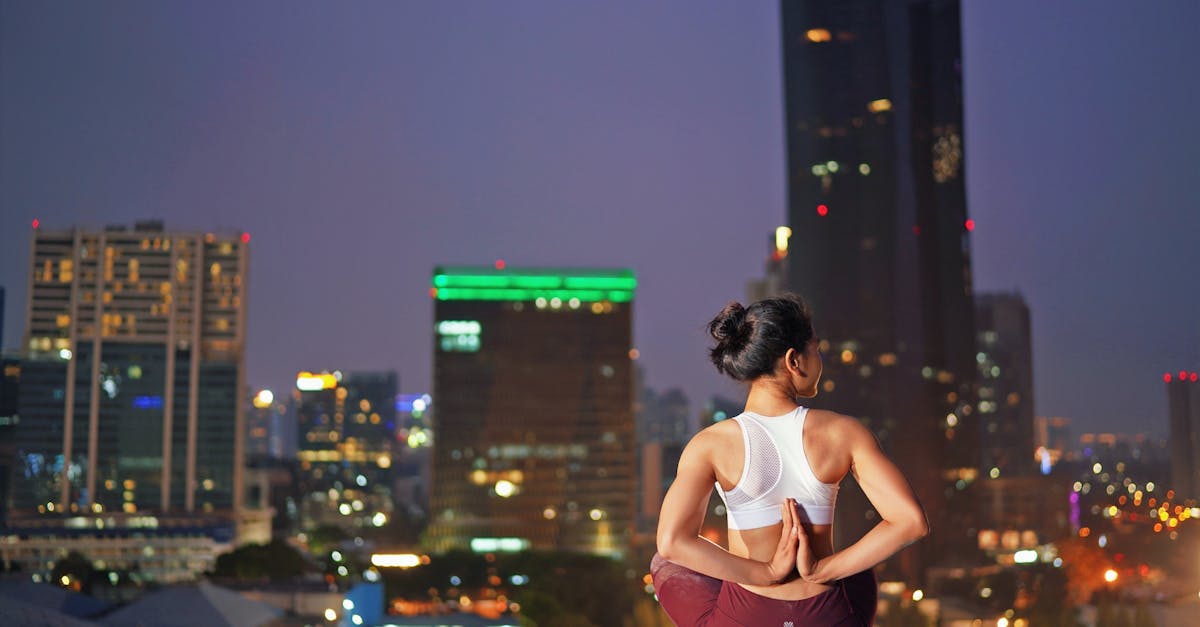 A woman doing yoga on a rooftop with a cityscape backdrop at night, promoting relaxation.