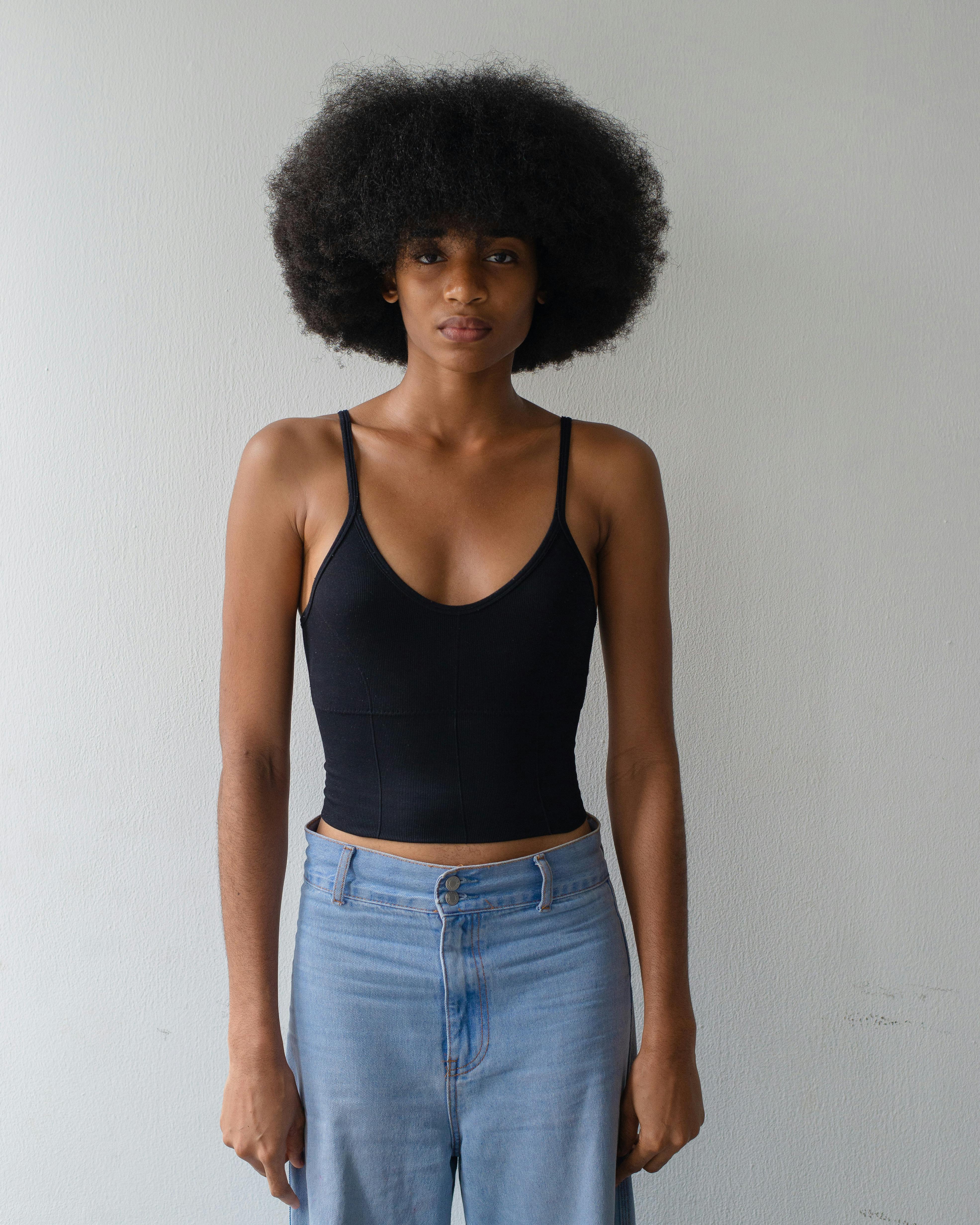 Gratis Portræt af en elegant afrikansk model med naturligt hår i et afslappet outfit indendørs. Perfekt stockfoto til mode- og livsstilsindhold. Lagerfoto