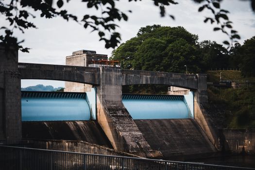 A concrete dam amidst lush greenery in Scotland, showcasing industrial architecture.