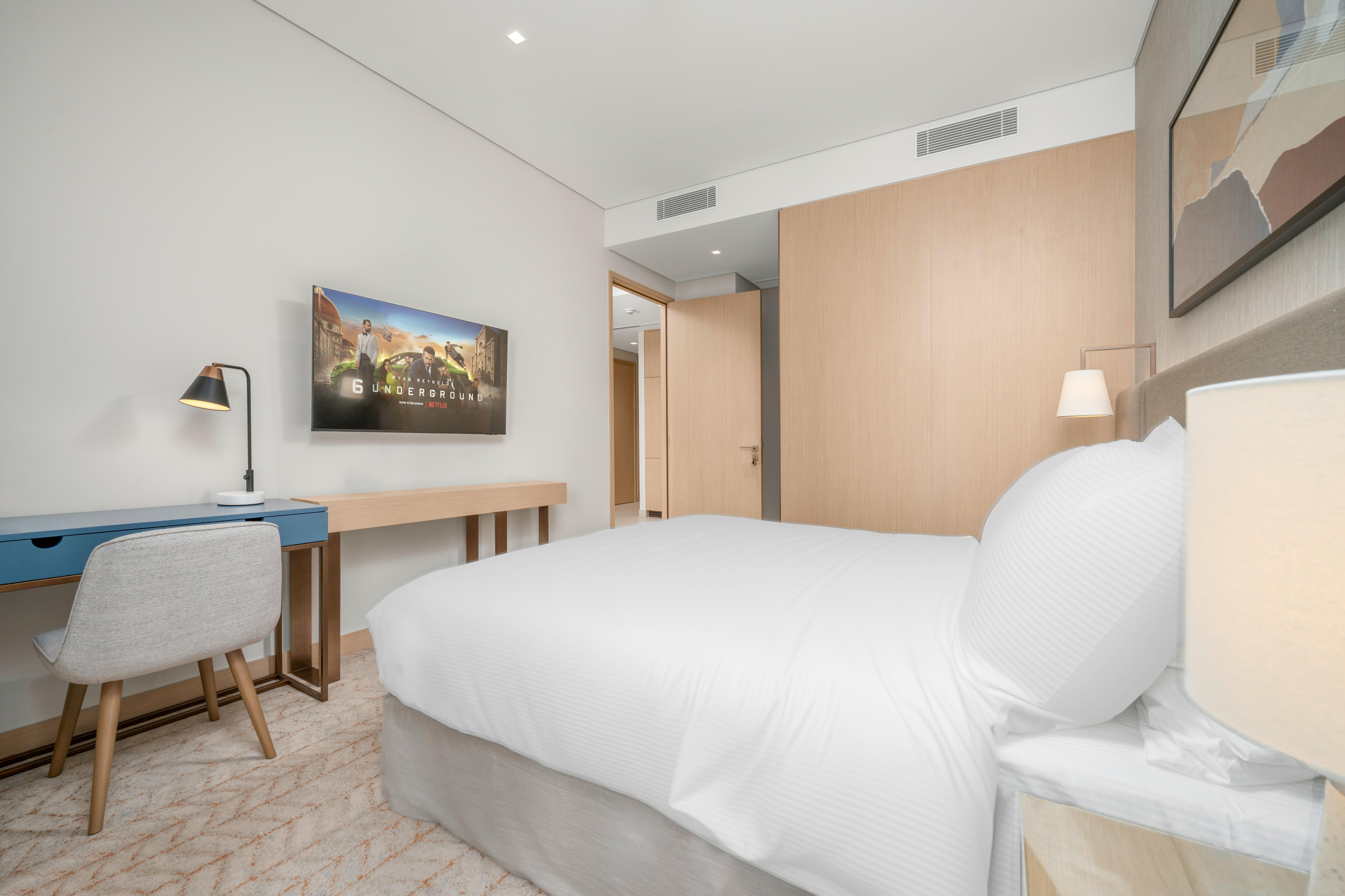 Kompaktes Gästezimmer mit hellem Home-Office-Schreibtisch und Schlafsofa in beige-grauer Farbpalette