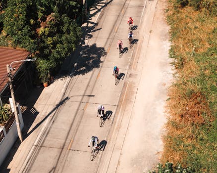 Aerial view of cyclists riding on a sunny street in Thailand, perfect for travel and lifestyle themes.