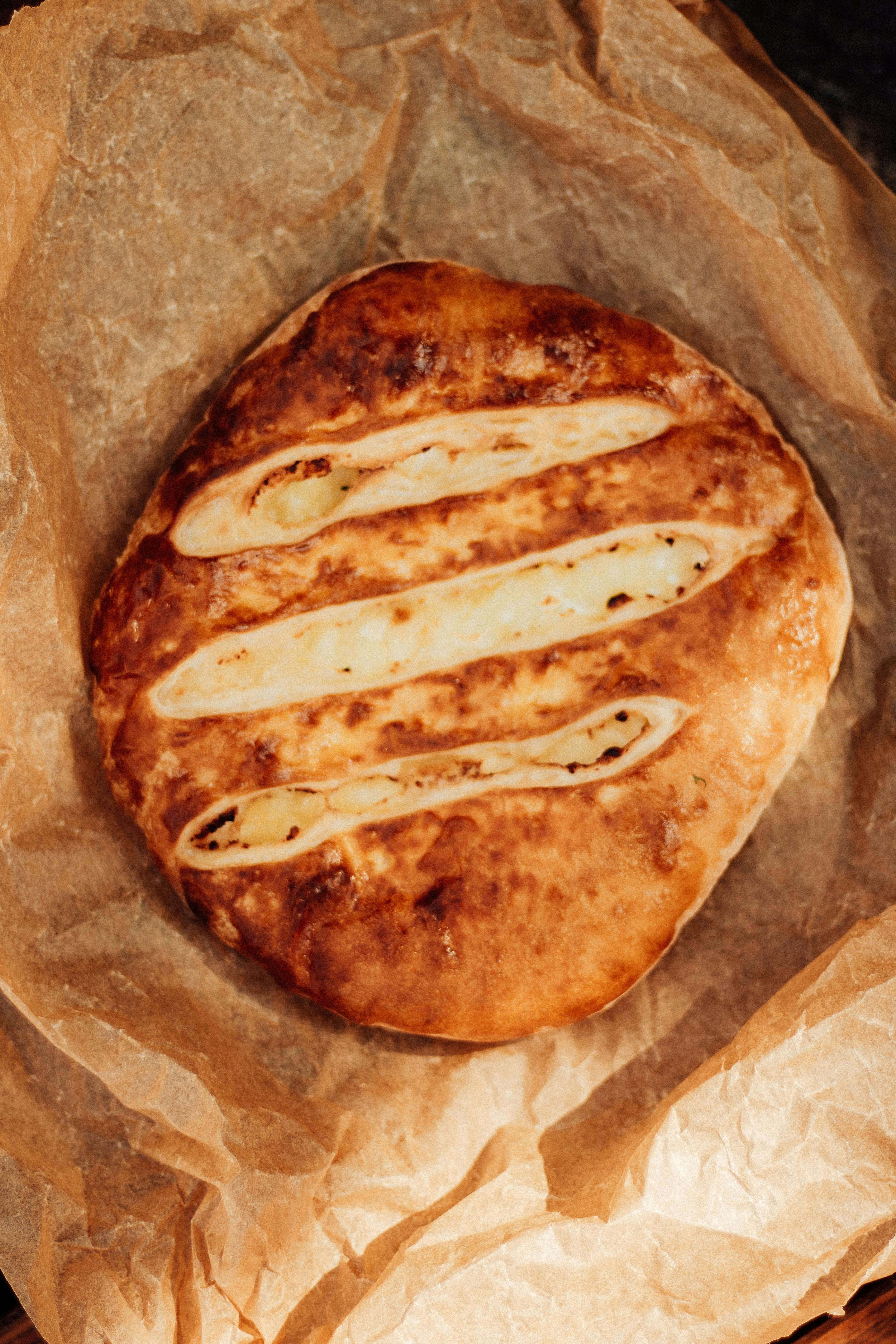 Close-up of traditional Georgian cheese bread, freshly baked and golden, on parchment paper.