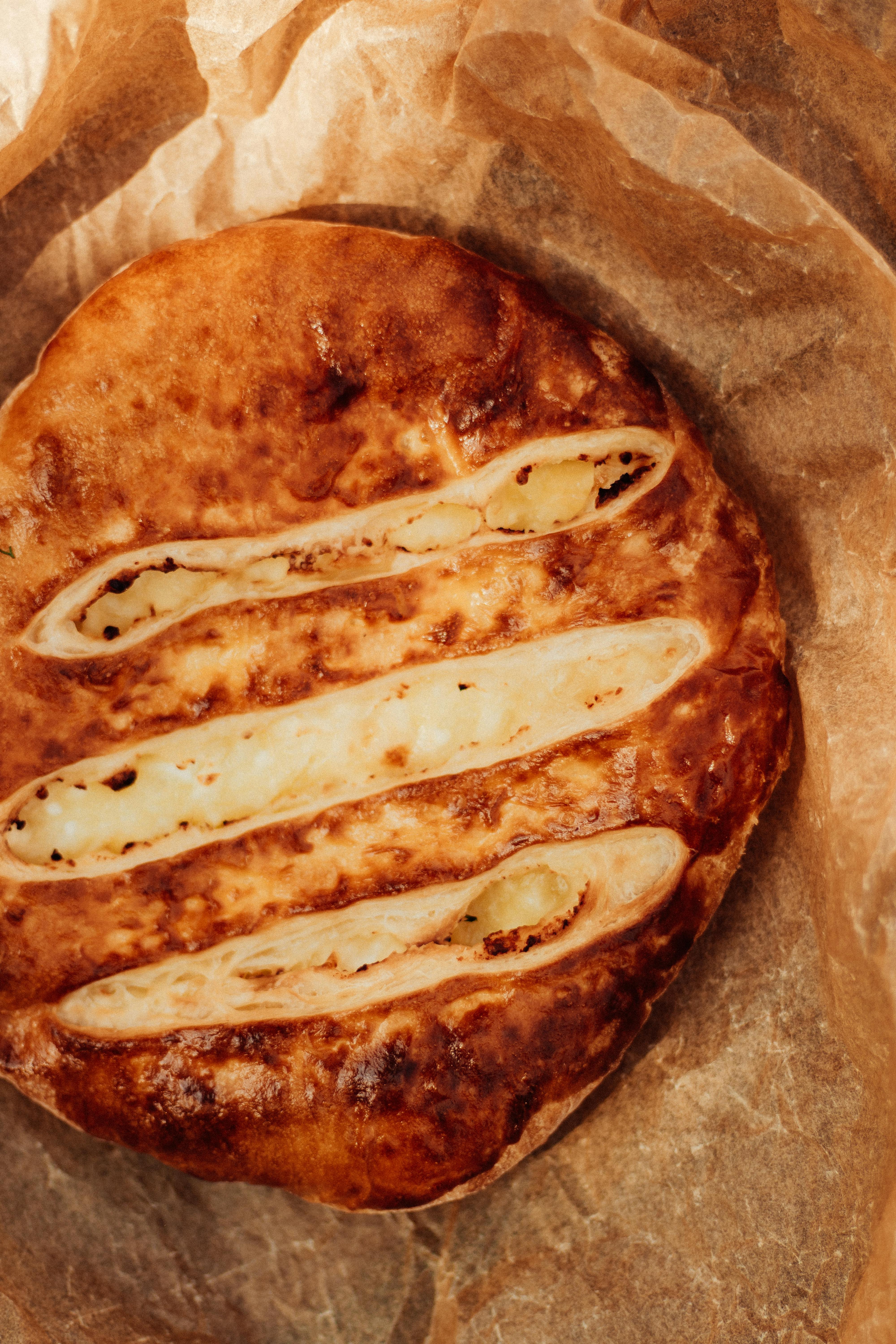 Close-up of homemade Georgian Khachapuri bread with cheese filling on parchment paper.