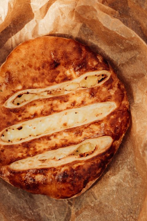 Free Close-up of homemade Georgian Khachapuri bread with cheese filling on parchment paper. Stock Photo