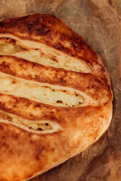 Free Close-up of golden brown homemade cheese bread on a baking sheet, showcasing texture and crust. Stock Photo