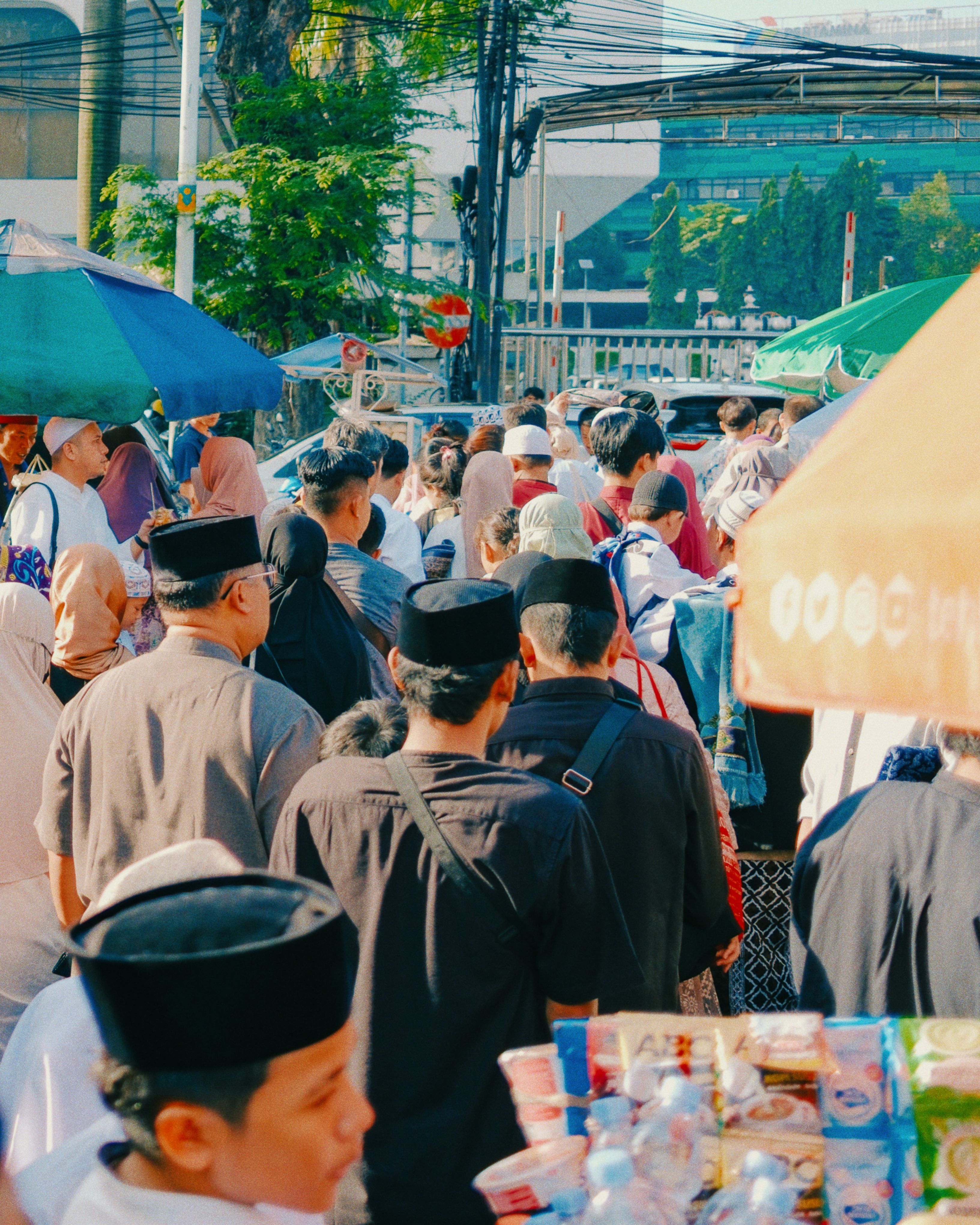 A bustling street market in Jakarta with a diverse gathering of people in Islamic attire.