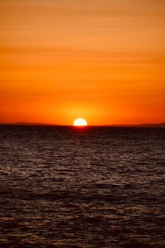 Captivating sunrise over the ocean with a bright orange sky reflecting on the water.