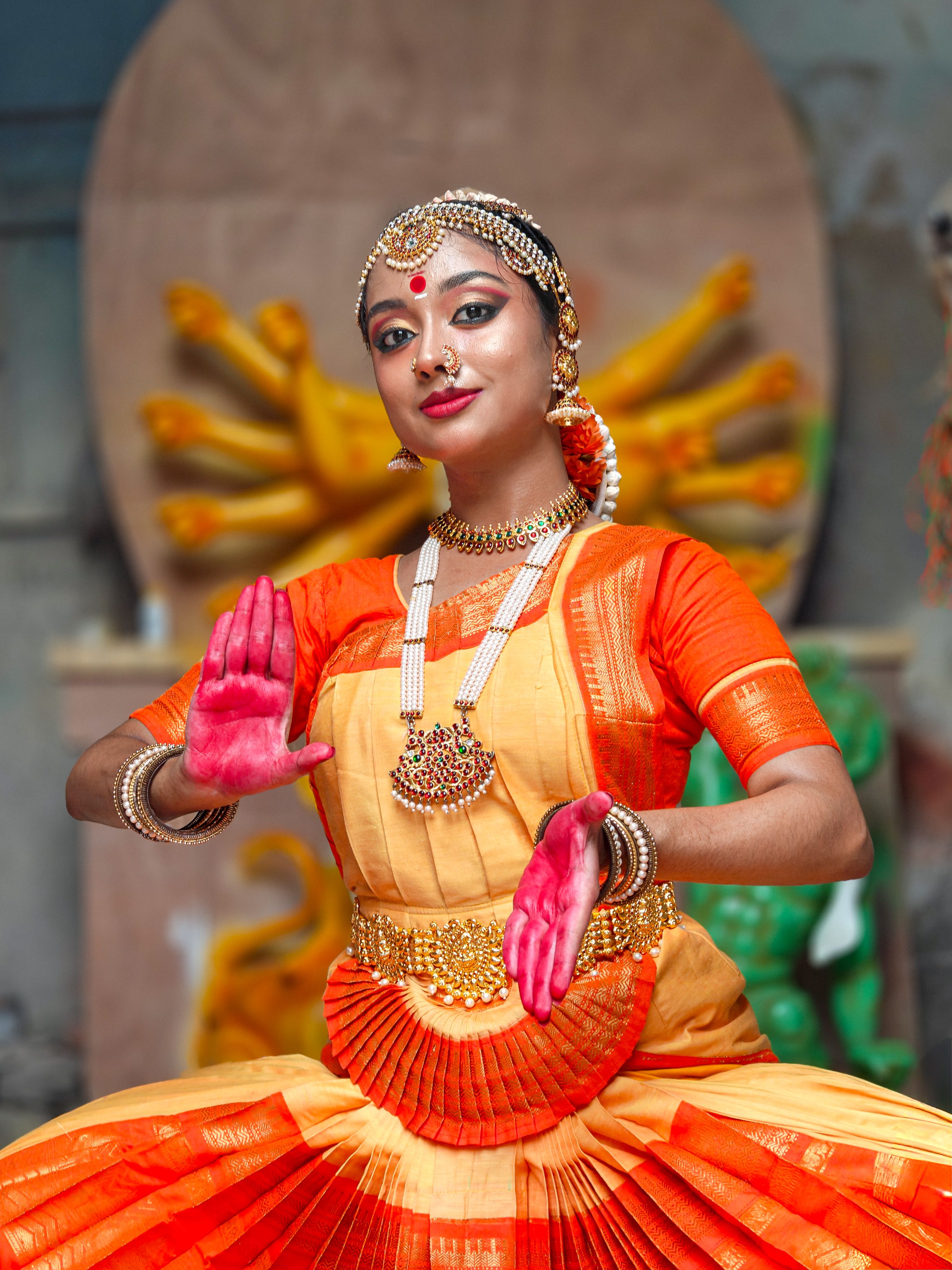 A skilled Bharatanatyam dancer poses gracefully, adorned in traditional attire with vivid colors.