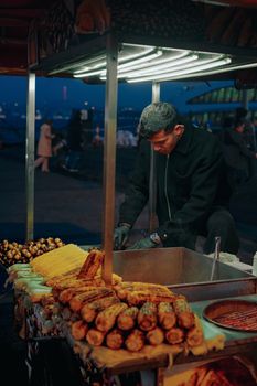 A street vendor grills corn at a bustling nighttime market in Istanbul, Turkey.