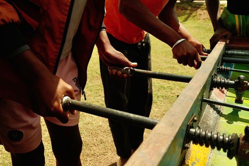 Free Several young adults engage in a lively outdoor foosball game under the sun. Stock Photo