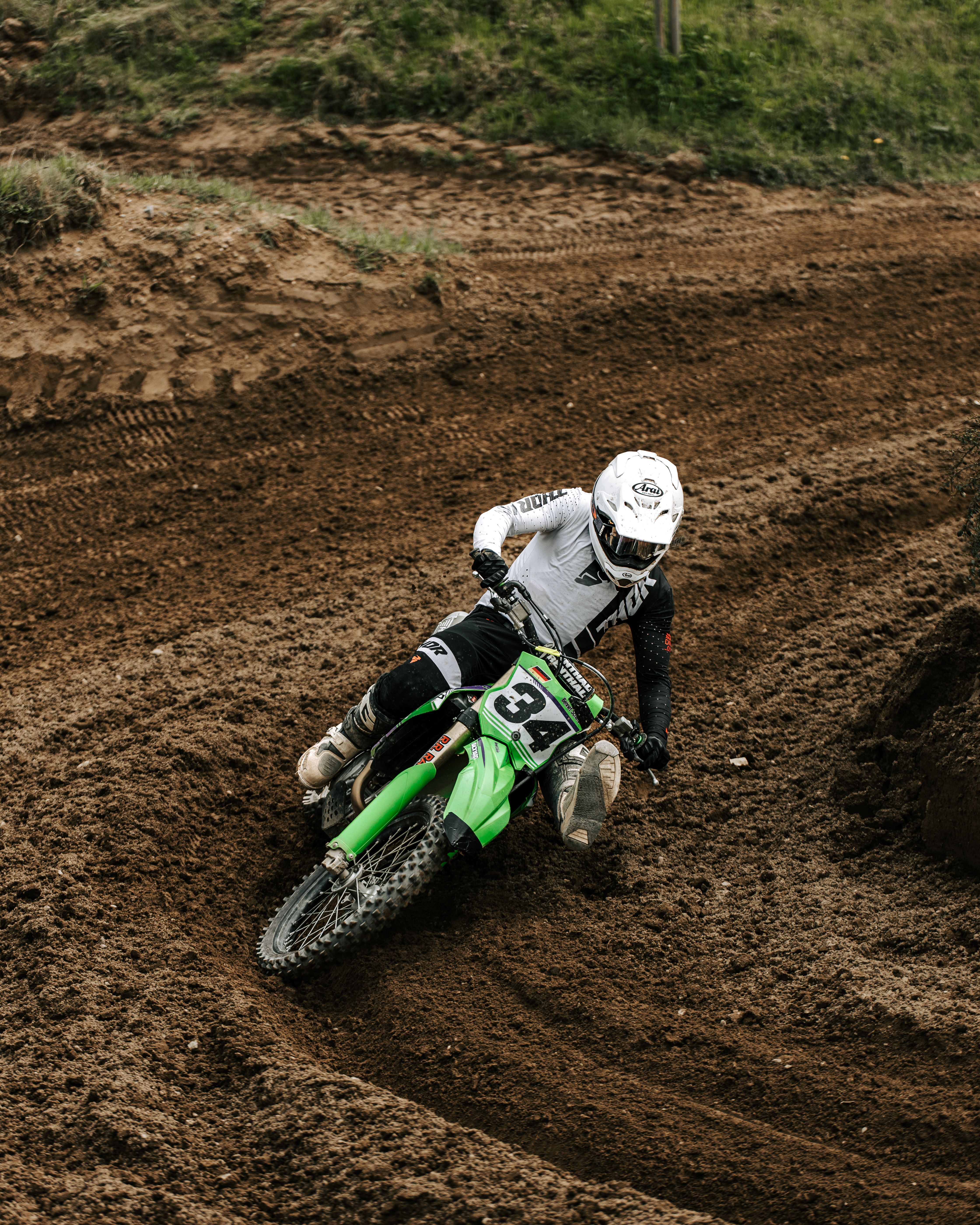 Motocross rider taking a sharp turn on a dirt track, showcasing speed and control.