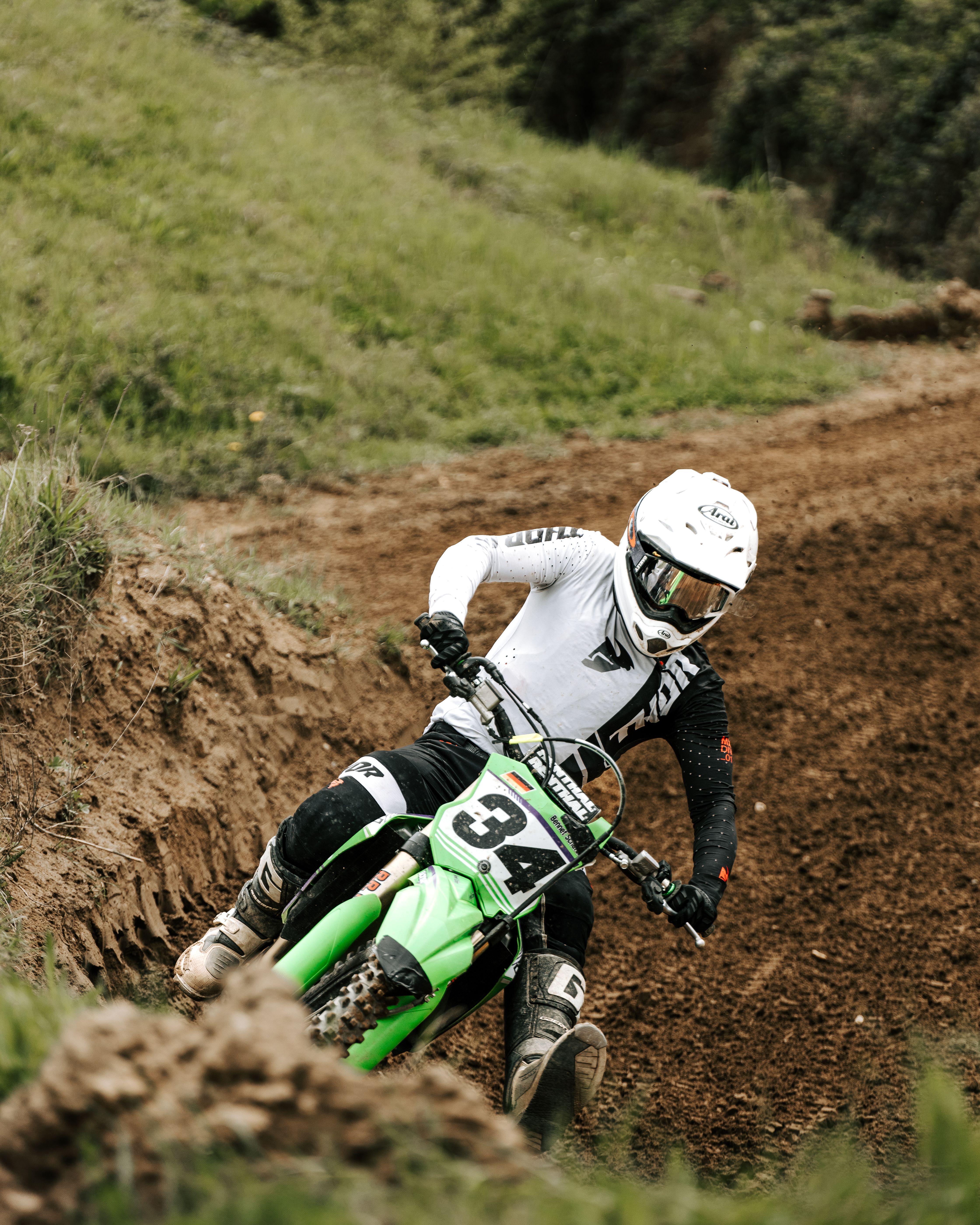Motocross rider skillfully navigating a dirt track curve, showcasing speed and agility in a dynamic race scene.