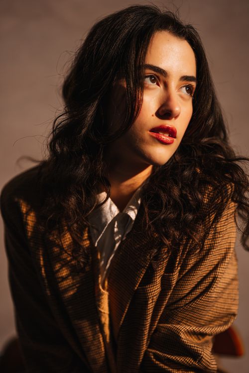 Free Studio portrait of a thoughtful woman looking aside, with warm lighting accentuating her features. Stock Photo
