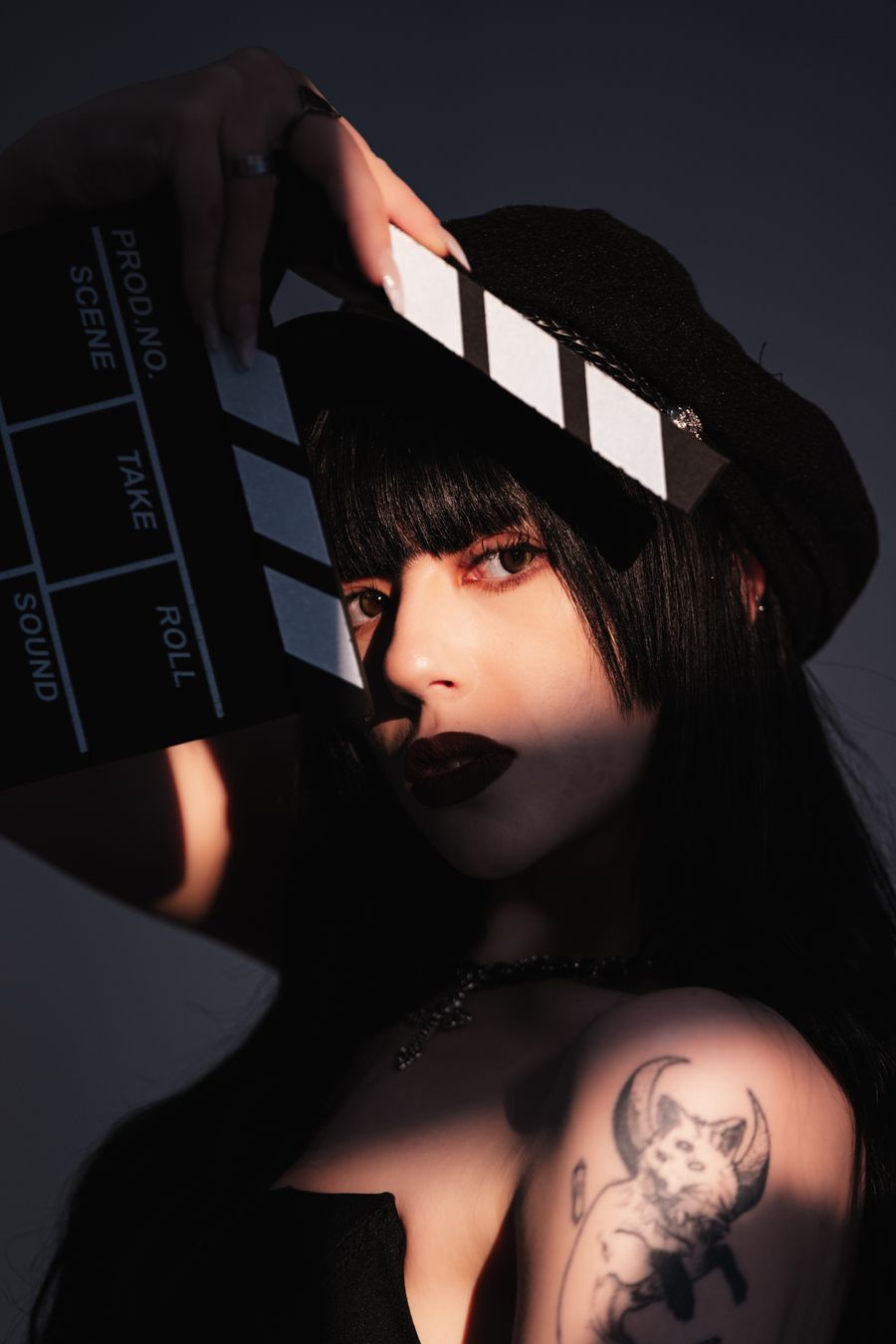 Moody portrait of a woman holding a clapperboard in studio lighting