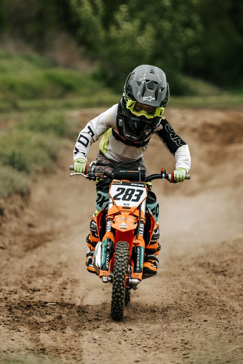 Free Young rider on dirt bike racing outdoors, showcasing motocross skills and gear. Stock Photo