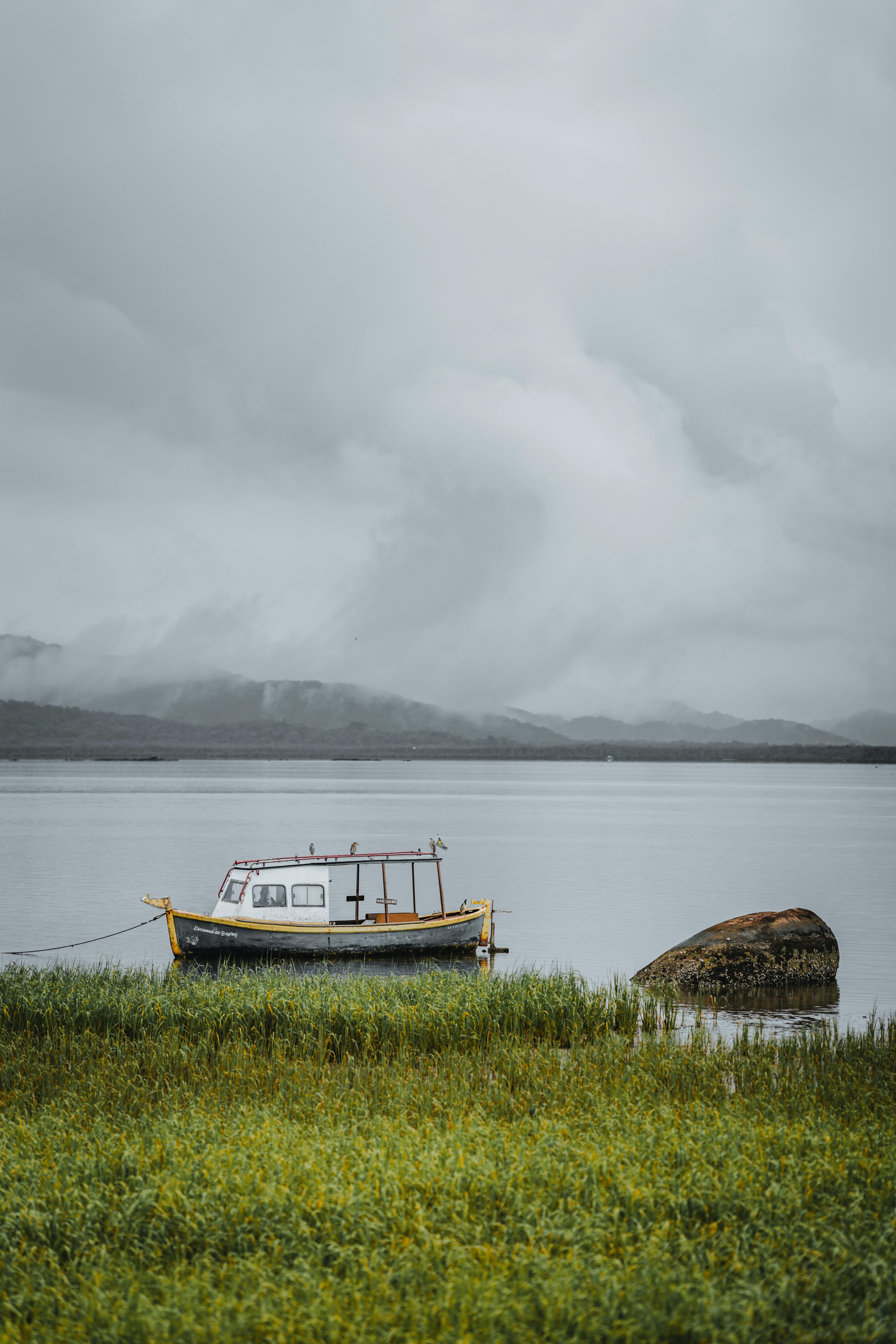 A lone boat anchored near rocks in a foggy harbor at Antonina, Paraná, Brazil.