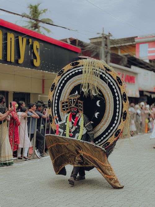 Free Kerala street parade showcasing vibrant traditional Theyyam performer with intricate costume and headgear. Stock Photo