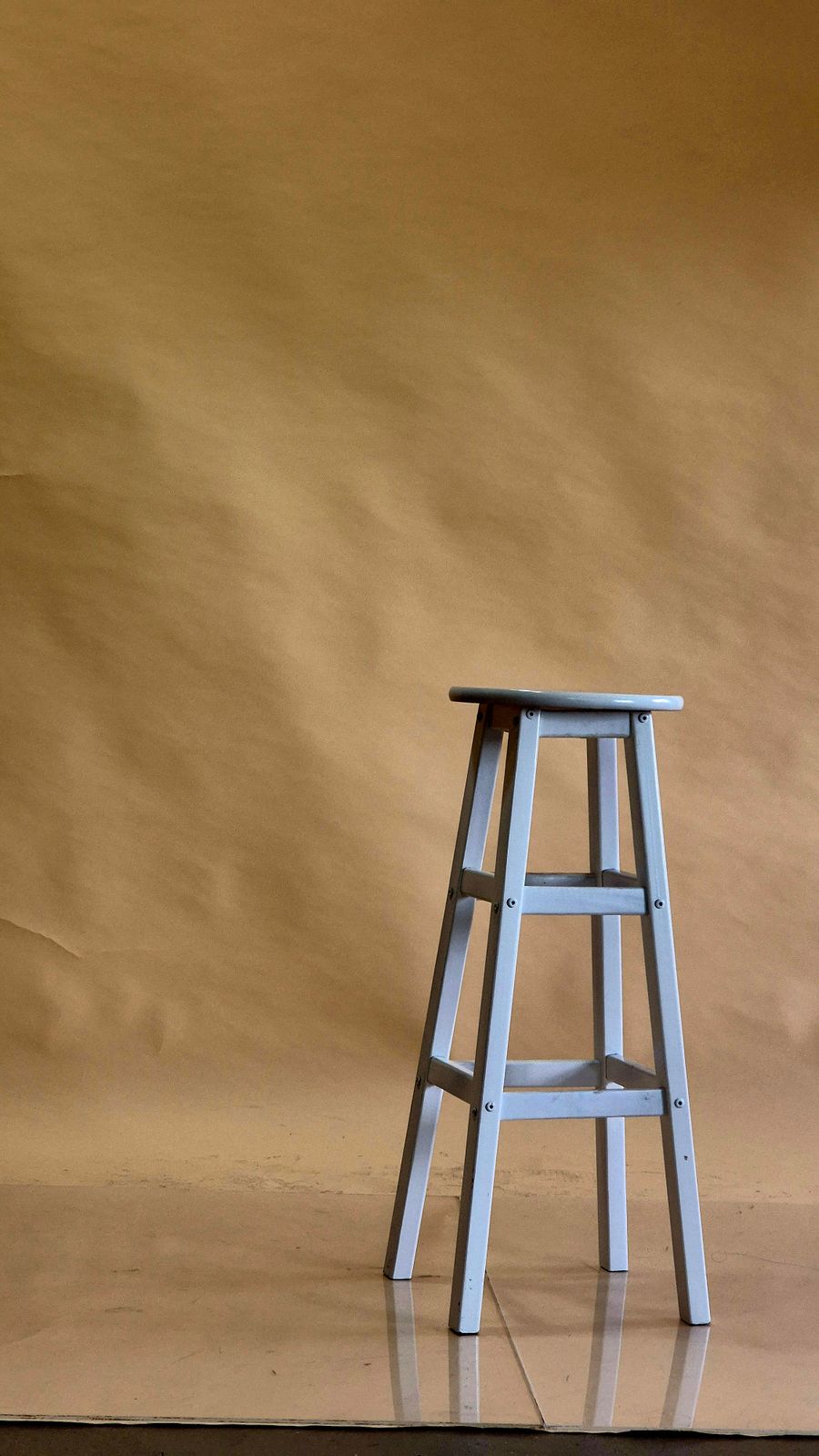 Wooden stool against a plain brown backdrop — photo by Garfield Besa on Pexels