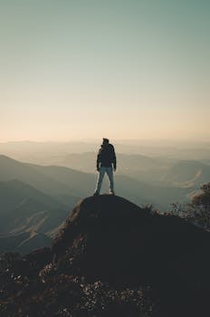 一个男人在山顶上，享受着令人惊叹的景色，拥抱自由与冒险
