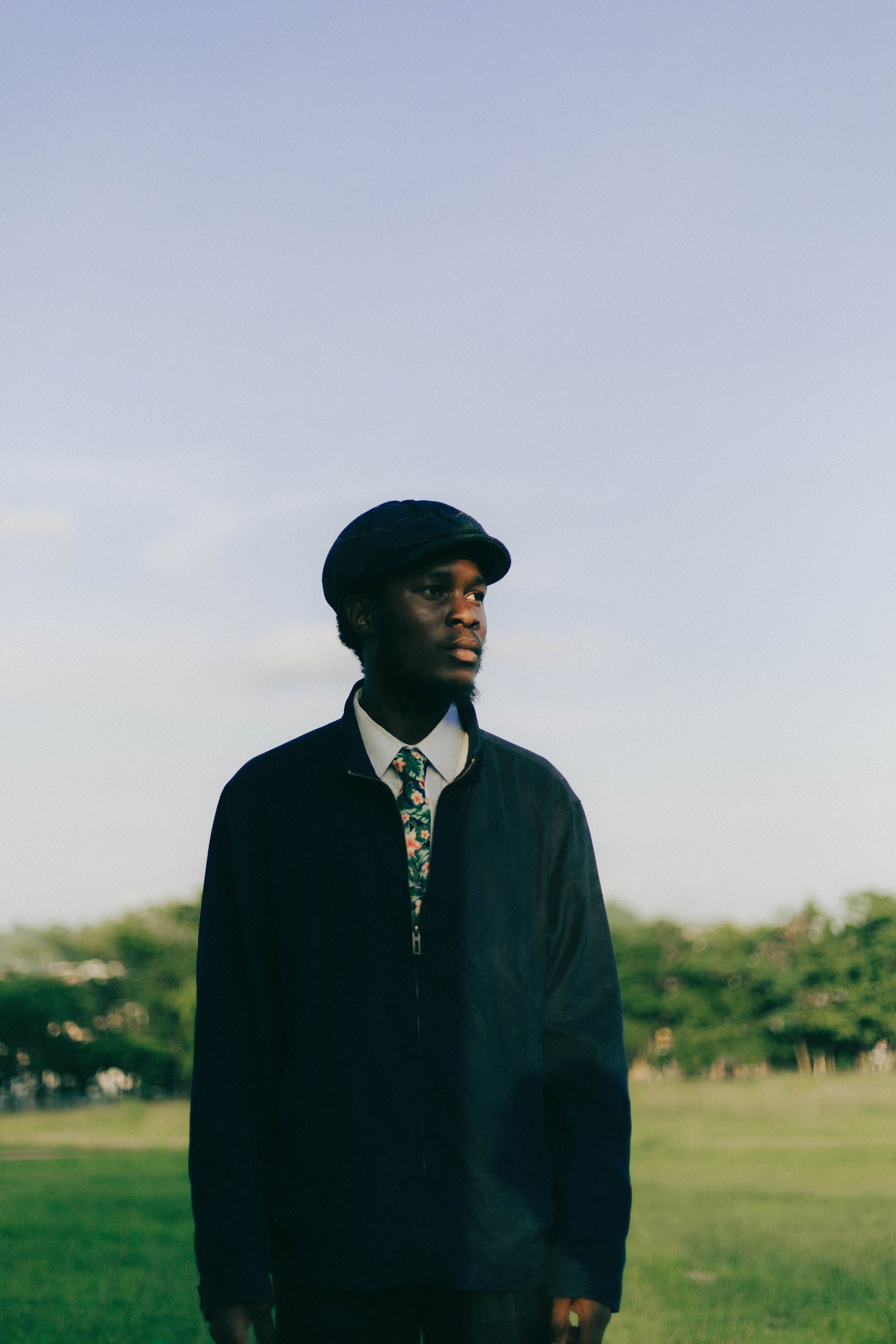 A man dressed elegantly outdoors with a scenic backdrop in Abuja, Nigeria.