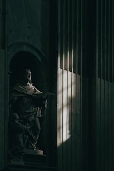 Intricate Roman statue engulfed in shadow and light in a historic Lazio building.
