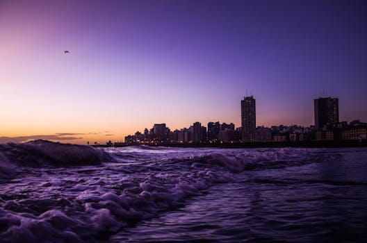 Vibrant twilight view of Mar del Plata's coastline with waves and city skyline in silhouette.