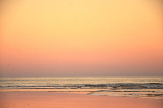 Serene view of dawn over the sea at Mar del Plata, Argentina, with soft waves and colorful sky.
