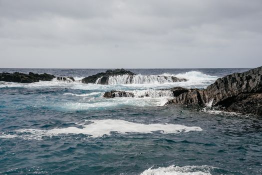 Experience the dynamic waves crashing on rugged volcanic rocks in Santa Catalina's dramatic coastal scene.