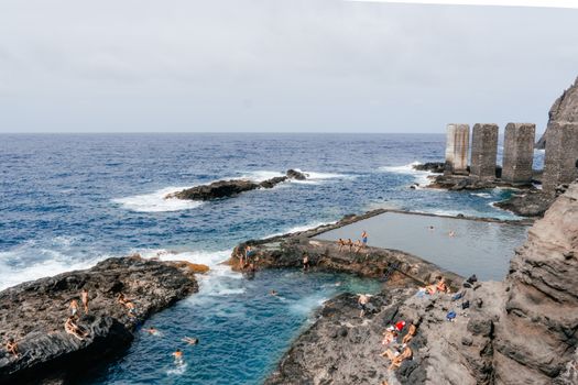 Swimmers enjoy the natural pools and rugged coastline of Pescante de Hermigua, providing a unique coastal swimming experience.