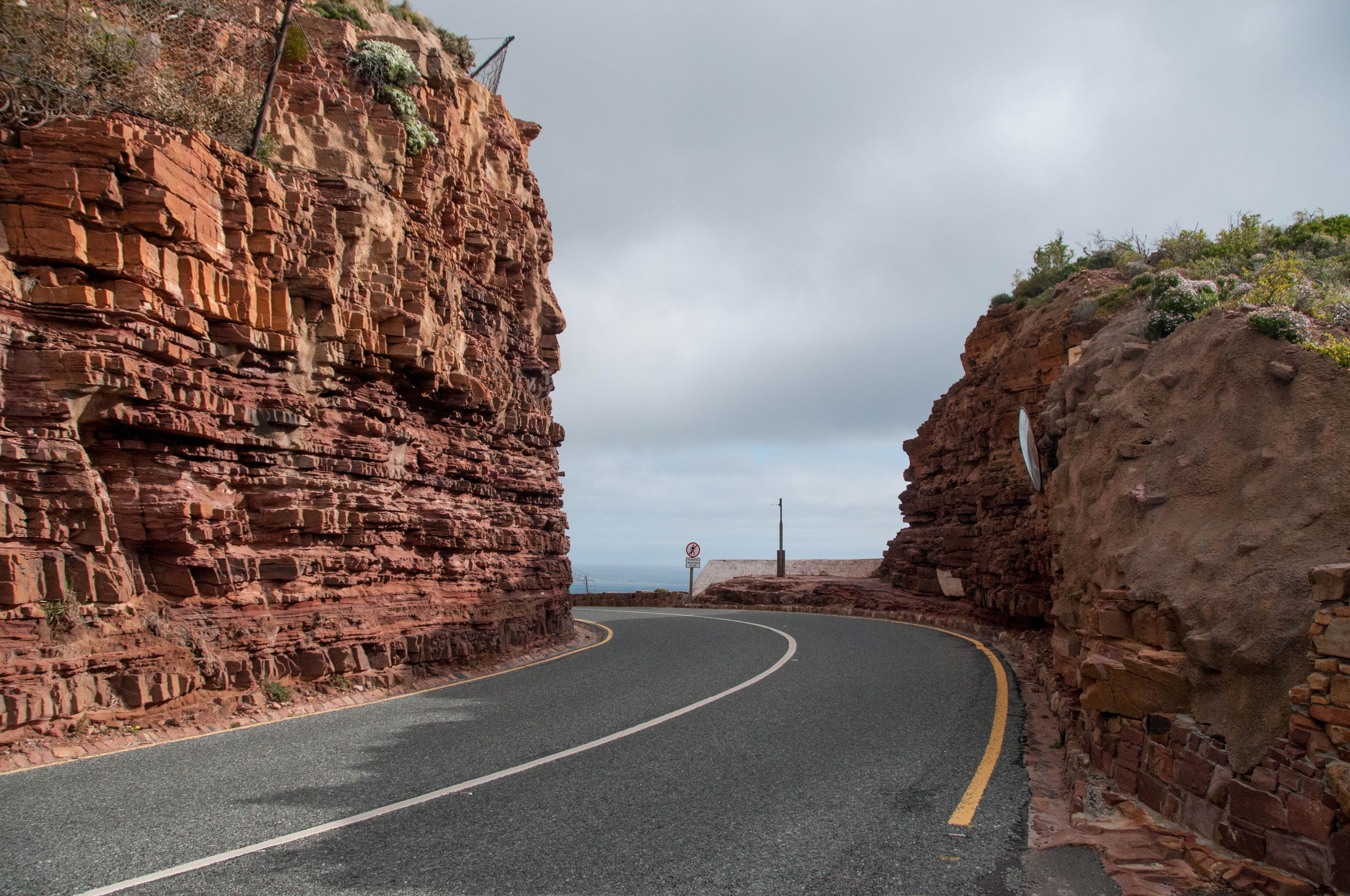 Winding road through red sandstone cliffs in Cape Town, showcasing natural beauty and adventure.