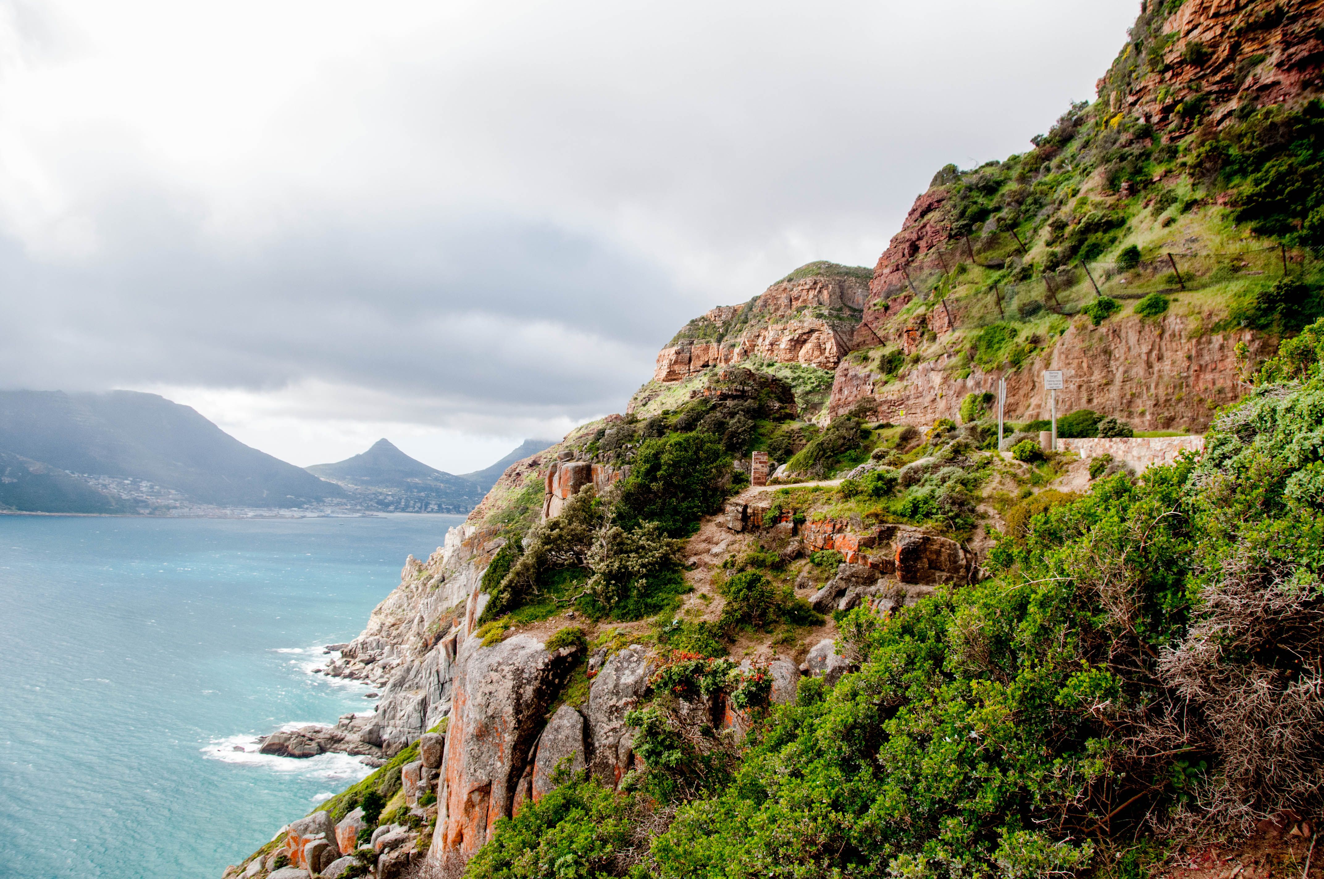 A narrow coastal road carved into a cliff face high above the Atlantic on the Cape Peninsula