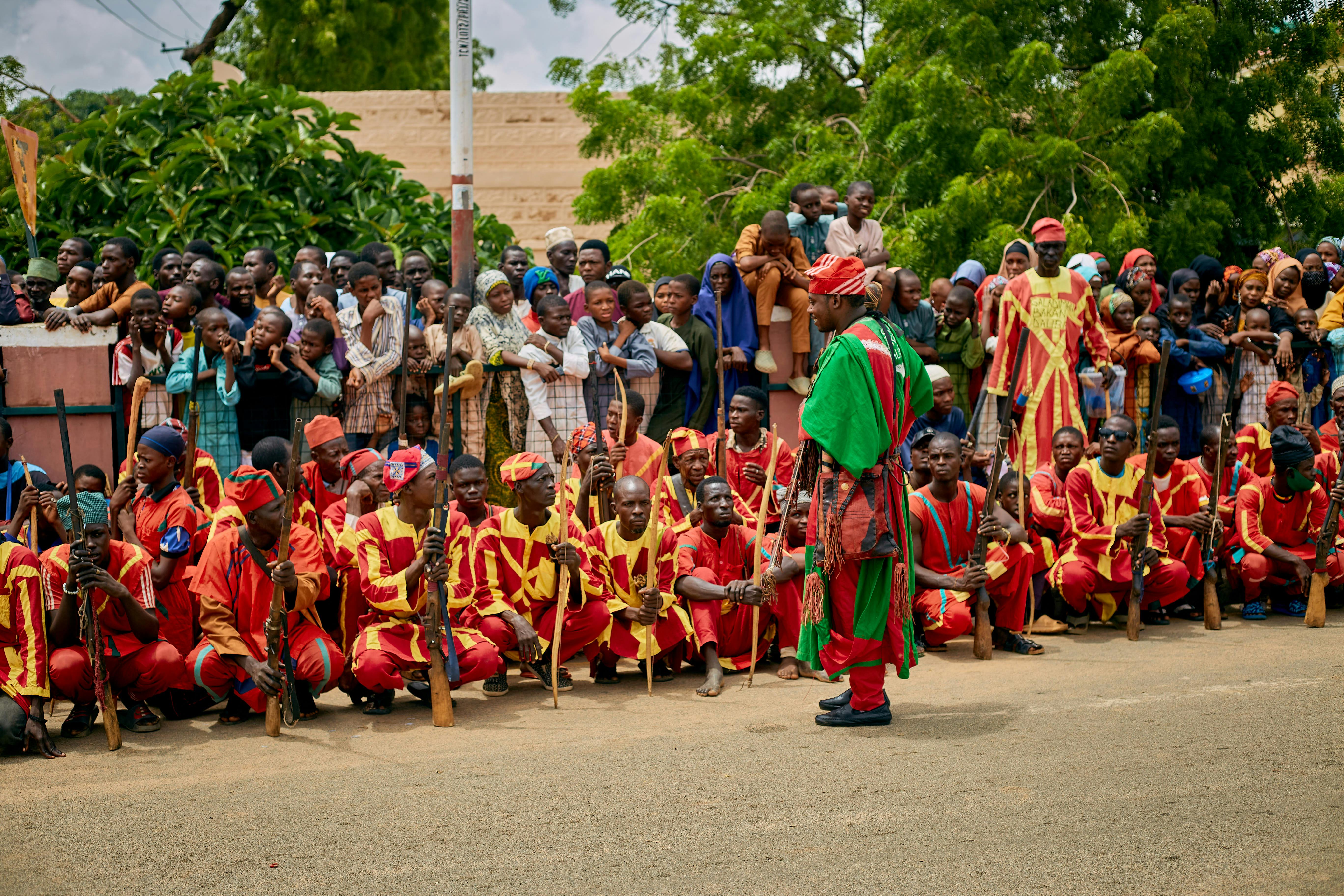 A vibrant cultural event in KT, Nigeria, featuring a group of performers in traditional attire and a crowd of spectators.