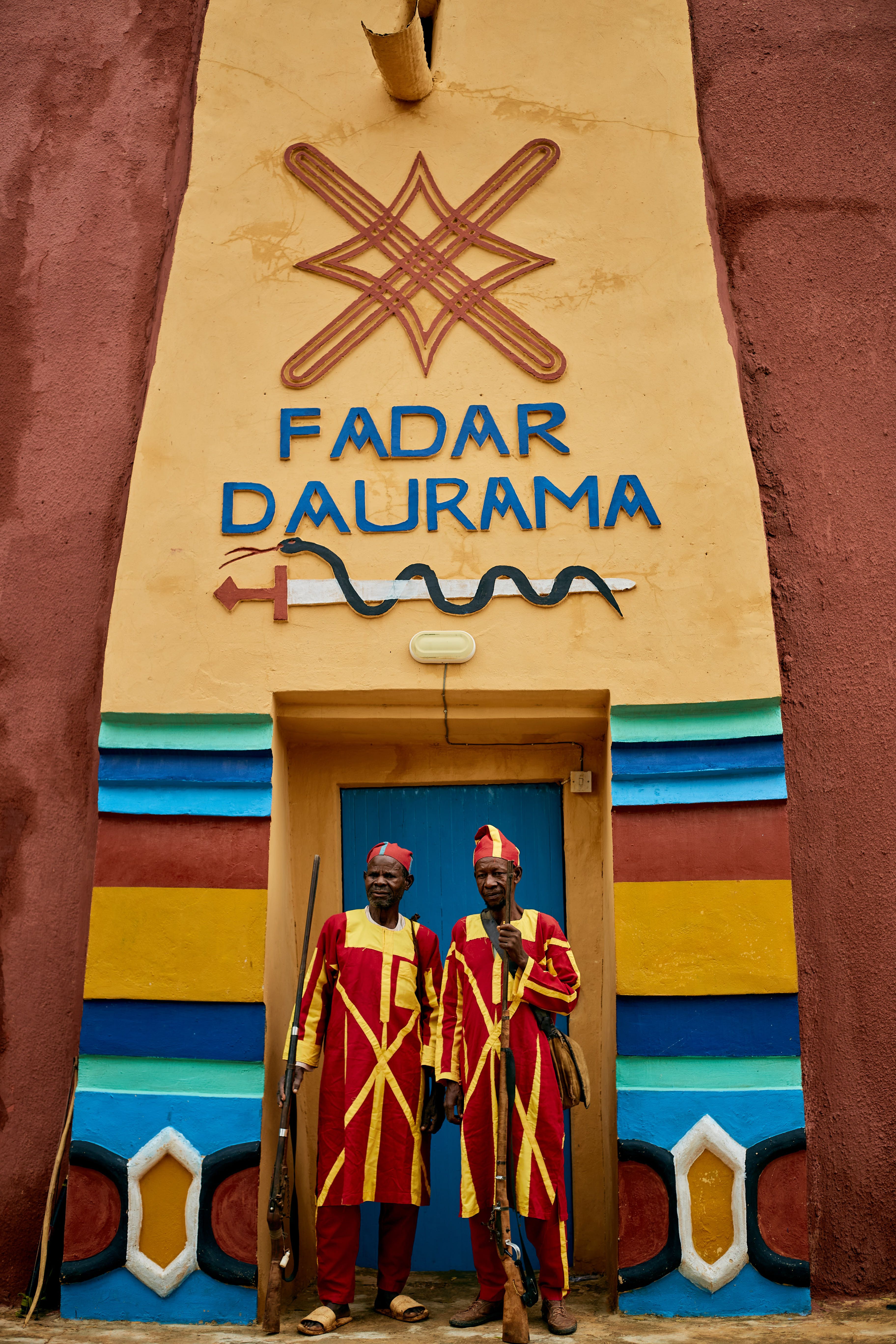 Two traditional guards in vibrant attire stand at the entrance of Fadar Daurama.
