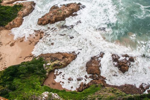Free Stunning aerial photograph of a rugged South African coastline with crashing waves and lush greenery. Stock Photo