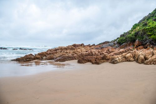Free Beautiful beach and rocky shoreline in South Africa under a cloudy sky. Stock Photo