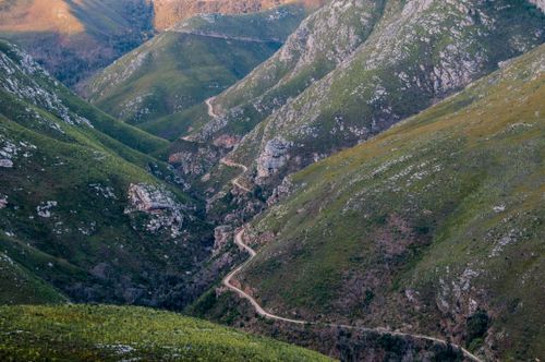 Free Scenic aerial view of a winding path through lush green mountains. Stock Photo