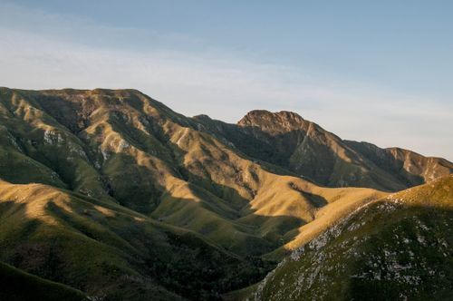 Free A breathtaking view of rolling mountains bathed in golden light under a clear sky. Stock Photo