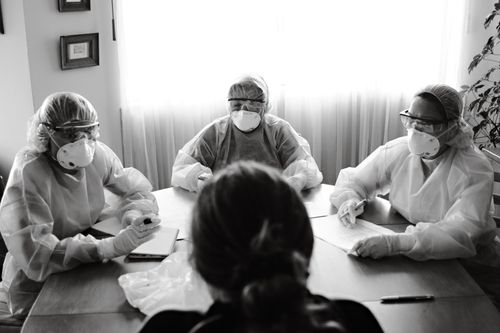 Free Black and white photo of healthcare team in PPE holding a meeting indoors. Stock Photo