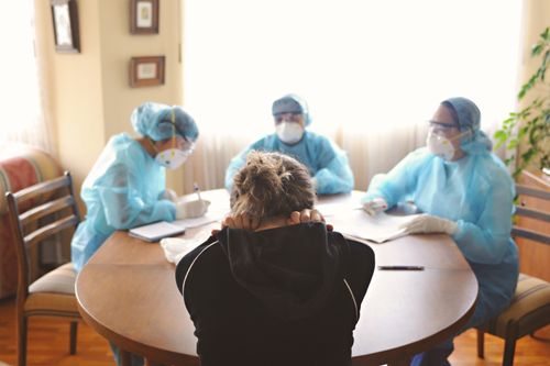 Free Medical professionals in PPE visit a patient at home, highlighting frontline healthcare efforts. Stock Photo