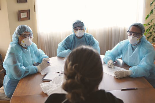 Healthcare workers in masks and gowns discussing patient care.
