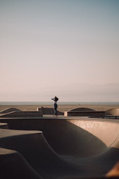 A lone skateboarder enjoys the Venice Beach skate park with the ocean in the background.