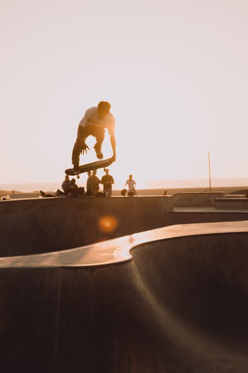 Free Silhouetted skateboarder doing an aerial trick at sunset in Los Angeles skatepark, capturing urban lifestyle. Stock Photo