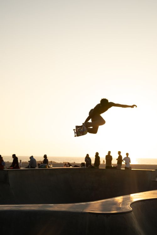 Free Silhouette of a skateboarder performing a trick at sunset in Venice Beach, Los Angeles. Stock Photo