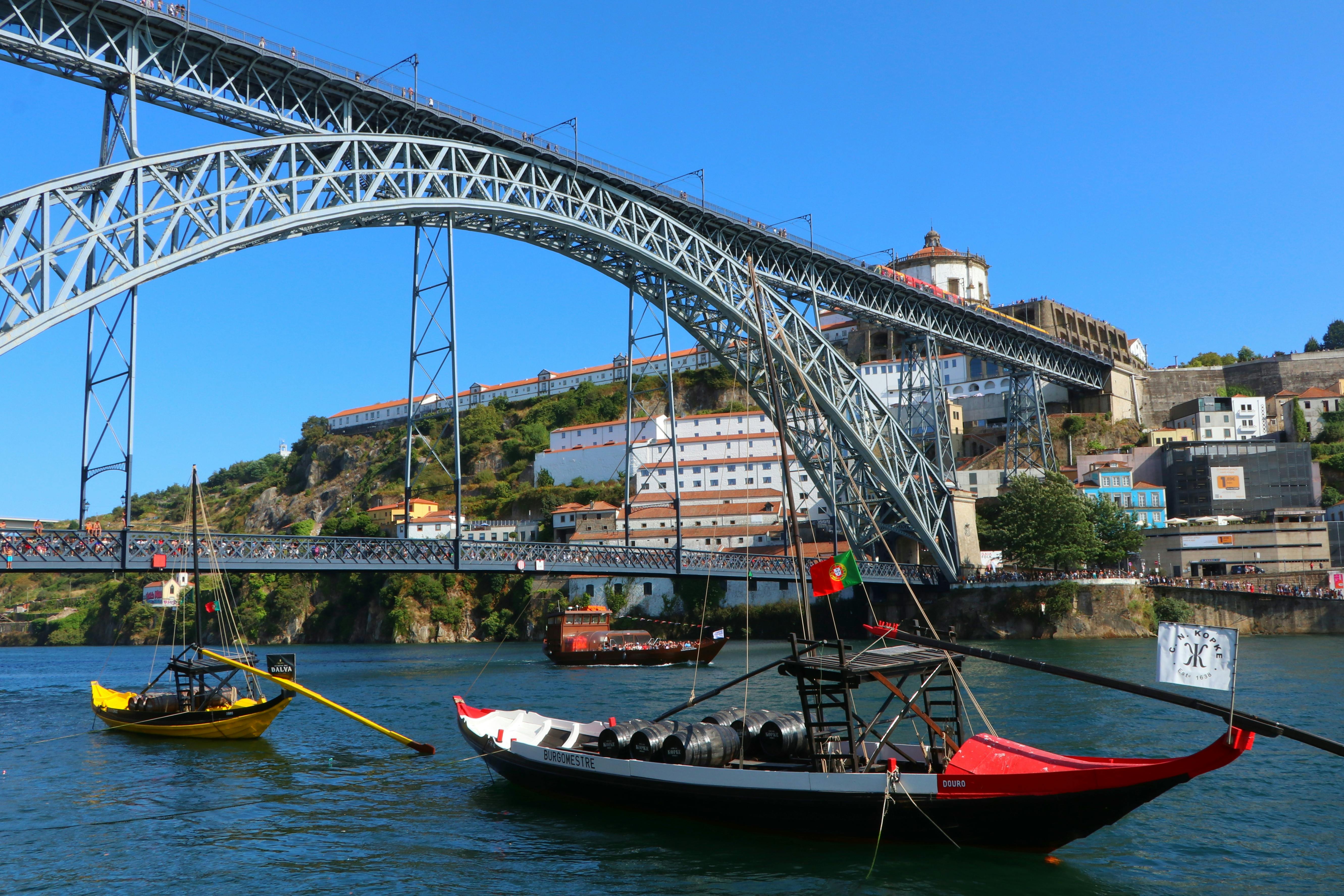 Scenic view of Dom Luís I Bridge spanning the Douro River in Porto, Portugal with traditional boats.