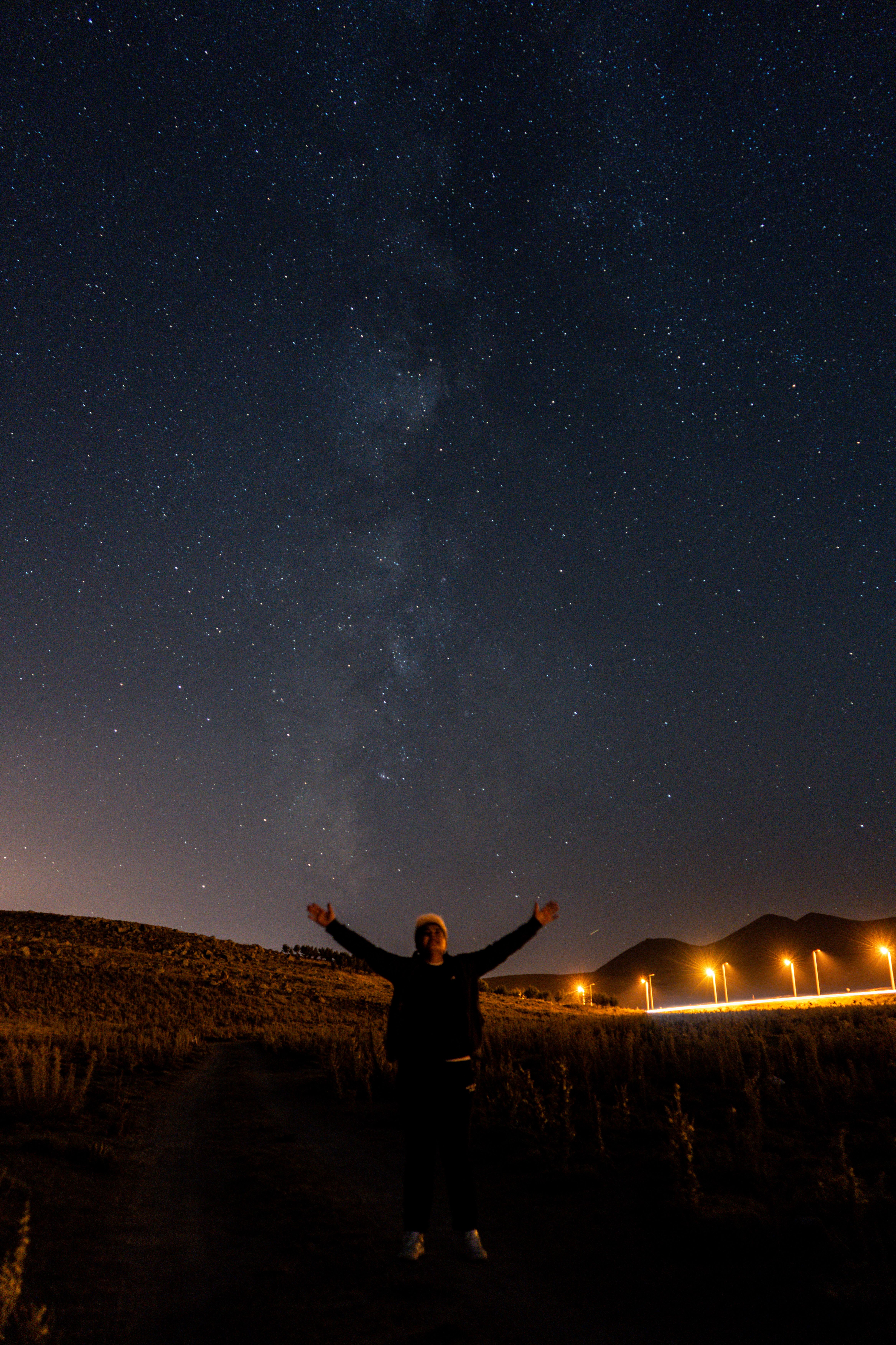 A person gazing at the stars under a clear night sky filled with stars and Milky Way.