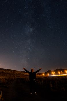 A person gazing at the stars under a clear night sky filled with stars and Milky Way.
