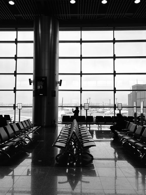 Free Serene view of an empty airport terminal with seating and window view of the runway. Stock Photo